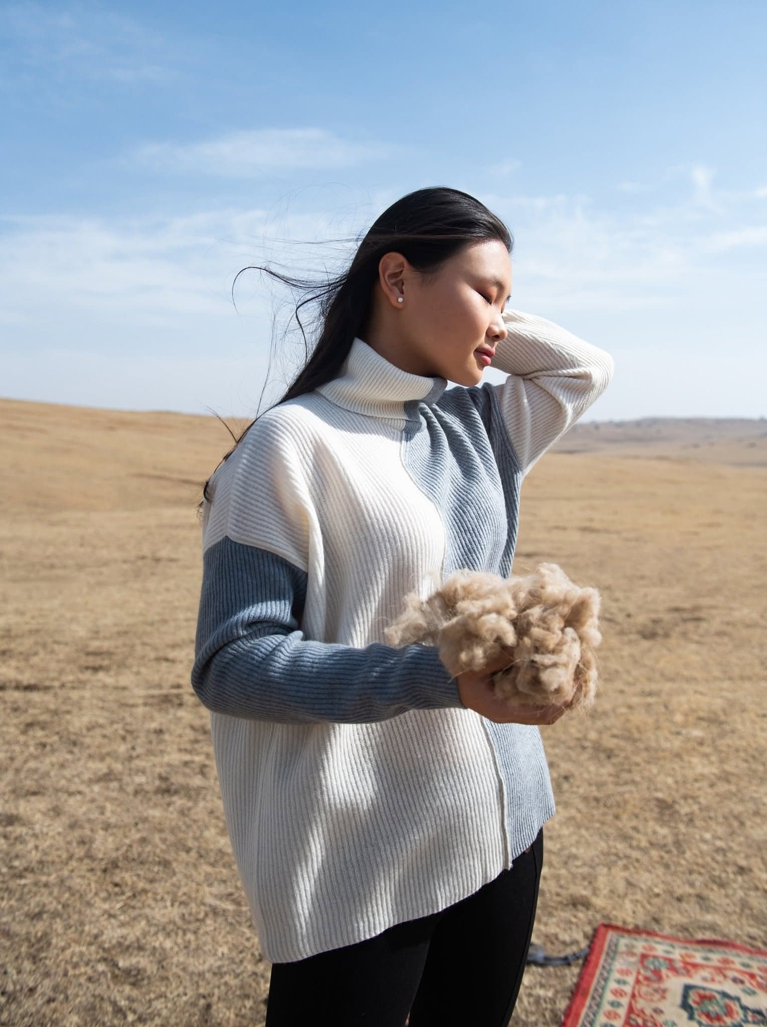 Femme tenant une poignée de fibre de cachemire brute dans la steppe mongole